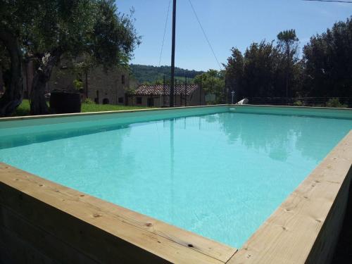 a large blue swimming pool with a wooden fence at La Collina Con Gli Ulivi in Perugia