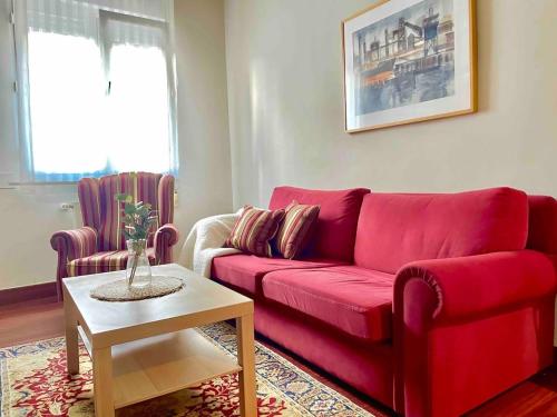 un divano rosso in soggiorno con tavolo di Casa PilarCasco Viejo Wifi a Bilbao
