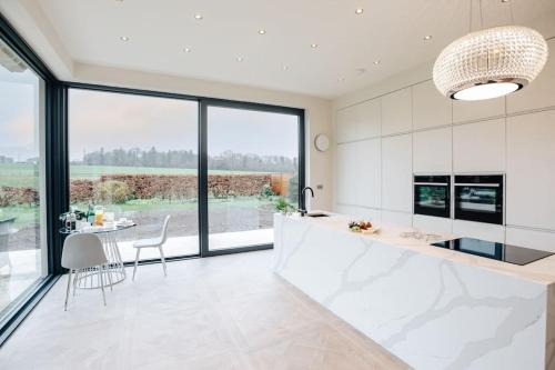 a kitchen with white cabinets and a table and chairs at Wisteria House - Sleeps 11 in Buckinghamshire