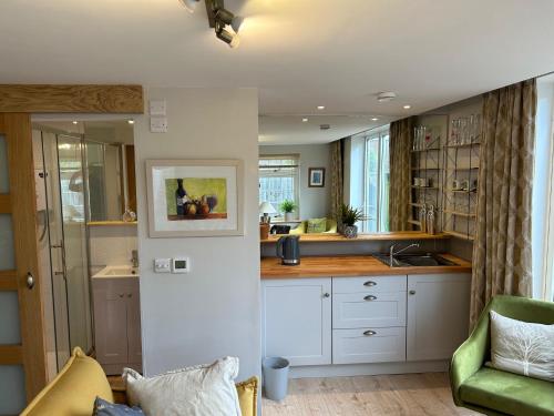 a kitchen with white cabinets and a green couch at Summer house studio in Cheltenham