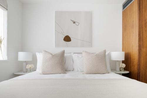um quarto com uma cama com lençóis brancos e almofadas em Luxury Central Mayfair Townhouse with A/C 3BR 3BA em Londres