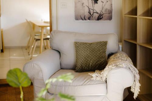 a white couch with a pillow in a living room at Bijou Niesenblick - traumhafter Seeblick - nahe Interlaken - idyllisch in Merligen