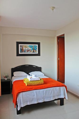 ein Schlafzimmer mit einem Bett mit einer orangefarbenen Decke in der Unterkunft Hotel Sengor in Urbanizacion Buenos Aires