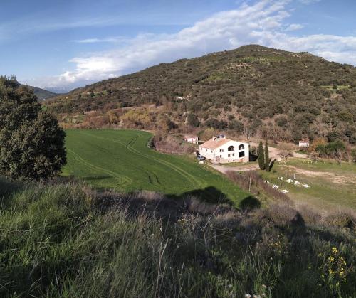 a white house in a green field with a mountain at Masia Molí de Tartareu in Tartareu