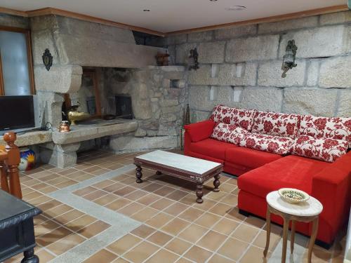 a living room with a red couch and a stone wall at Hotel O'Pazo in Vigo