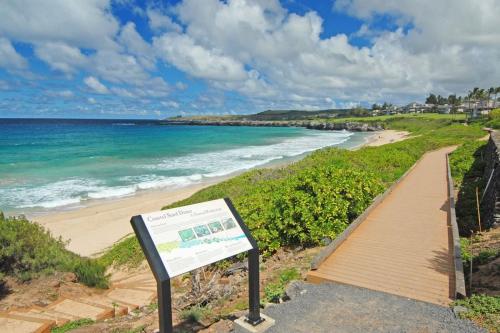 a boardwalk leading to a beach with a sign at 1722 Ridge in Kahana