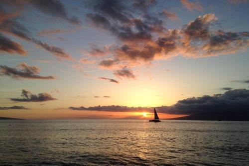 a sail boat in the ocean at sunset at 1722 Ridge in Kahana