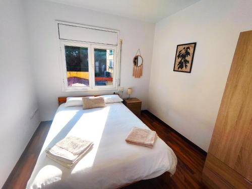una camera da letto con un grande letto bianco e una finestra di Apartamento en el centro de Playa de Aro a Platja  d'Aro