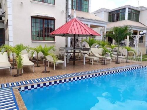 a pool with a table and an umbrella next to a building at Adorable 2bedroom homestay in Beau Bassin