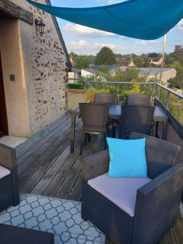 a deck with chairs and tables and a blue umbrella at gite odeau in Sargé-sur-Braye