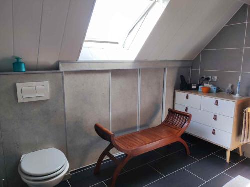La salle de bains est pourvue d'une chaise en bois et de toilettes. dans l'établissement Chambre proche paris JO 2024, à Chaumontel