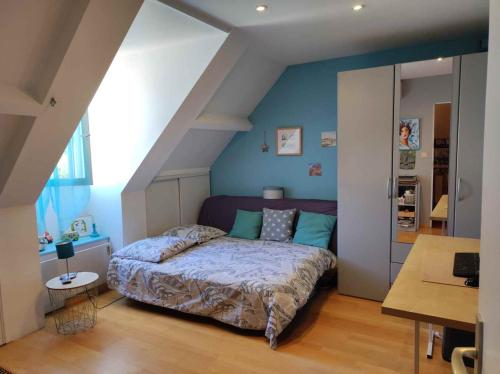 - une chambre avec un lit et un mur bleu dans l'établissement Chambre proche paris JO 2024, à Chaumontel