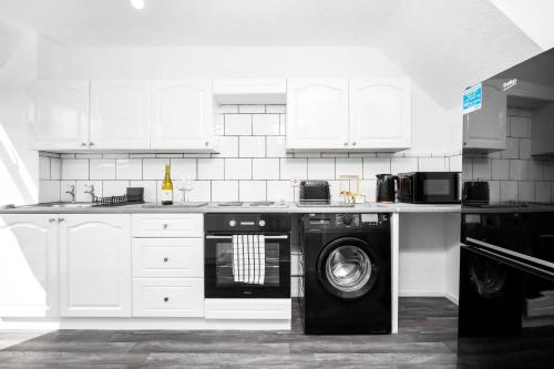 uma cozinha com uma máquina de lavar roupa e uma máquina de lavar roupa em Unique 2 Bedroom House - Free Wifi & Netflix - Garden - Parking - 4VC em Minworth