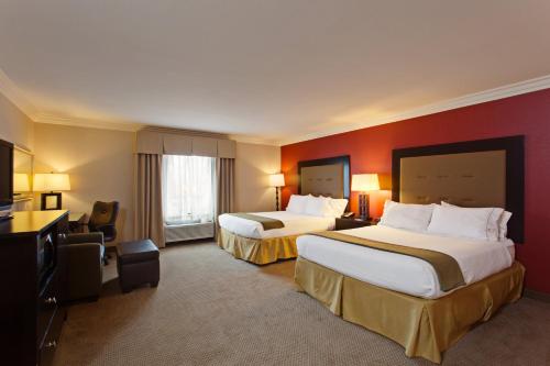Holiday Inn Express Hotel & Suites Twentynine Palms, an IHG Hotel في تونتي ناين بالمز: غرفة فندقية بسريرين وجدار احمر