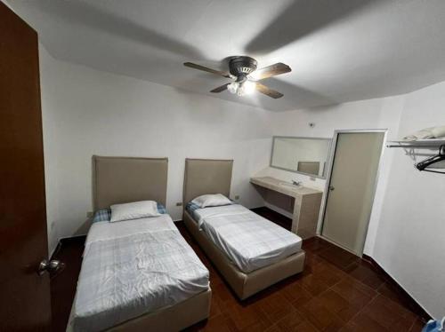 two beds in a room with a ceiling fan at Casa ROMA in Ciudad Obregón