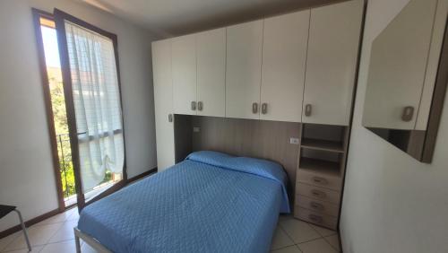 1 dormitorio con cama, armarios blancos y ventana en Isola, en Marina di Castagneto Carducci