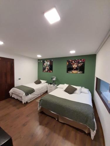 two beds in a room with green walls at 593 Hotel Boutique Baños in Baños