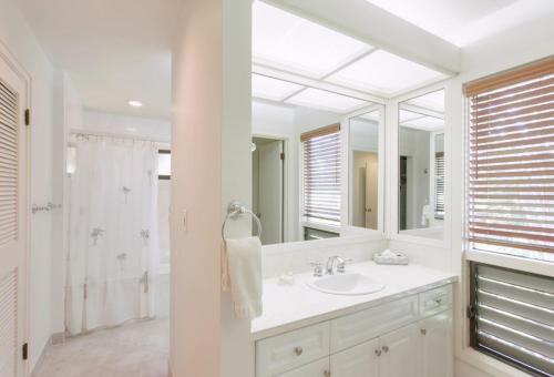 a white bathroom with a sink and a mirror at 2511 Ridge in Kahana