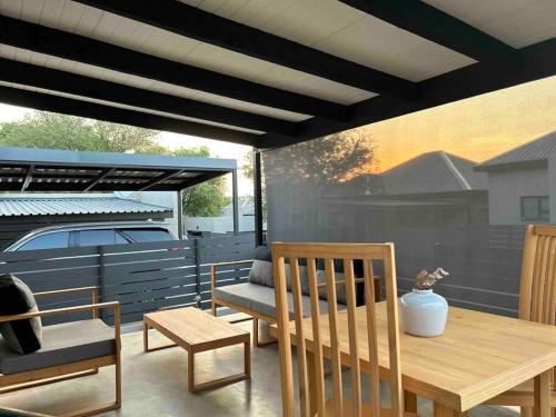 a patio with a wooden table and chairs and a bench at Comfortable home centrally located in Hoedspruit in Hoedspruit