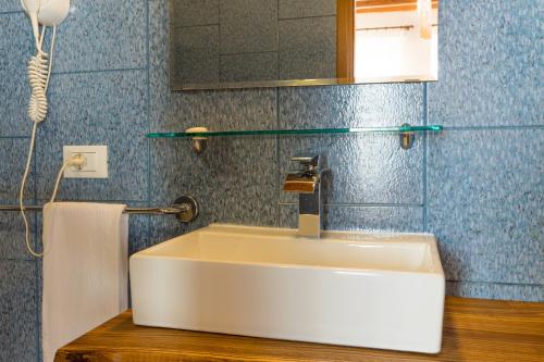 lavabo blanco en un baño con azulejos azules en Hotel Santo Stefano, en Campagnola Emilia