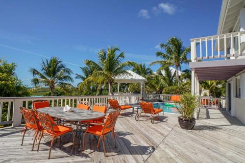una terraza con mesa, sillas y piscina en NEW Chalk Sound Home BBQ Pool Beach Steps Away en Providenciales