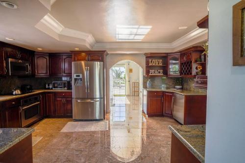 a kitchen with wooden cabinets and a stainless steel refrigerator at NEW Chalk Sound Home BBQ Pool Beach Steps Away in Providenciales