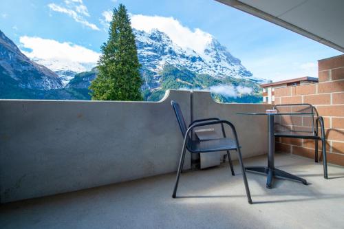 2 Stühle und ein Tisch auf einem Balkon mit Bergblick in der Unterkunft Hotel Grindelwalderhof in Grindelwald
