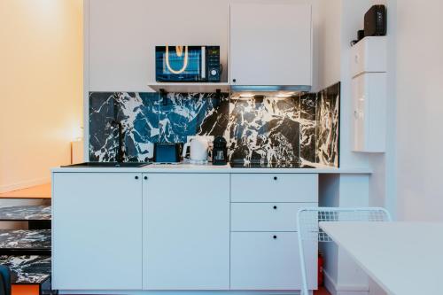 une cuisine avec des armoires blanches et des appareils bleus dans l'établissement Paillette, au Havre