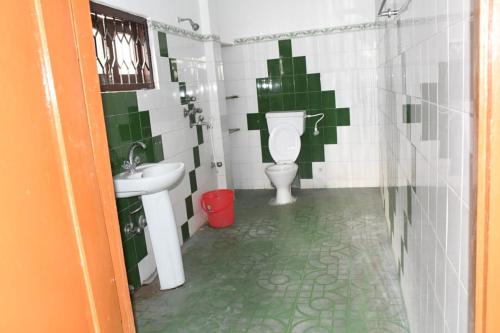 a green and white bathroom with a toilet and sink at Kajal's Home stay in Siliguri