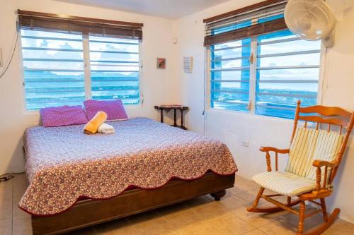 1 dormitorio con 1 cama, 1 silla y ventanas en Hill Top Apartment with 360 Degree Balcony View, en Vieques