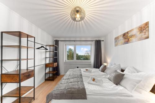 een slaapkamer met een groot wit bed en een kroonluchter bij VINFUL: Premium-Apartment mit Balkon und Parkplatz in Mülheim an der Ruhr