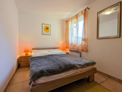een slaapkamer met een bed, een raam en een spiegel bij Ferienhaus Meerkieker mit Ostseeblick auf der Insel Poel - b48418 in Am Schwarzen Busch