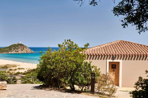 a building with a view of a beach at Baia Di Chia Resort Sardinia, Curio Collection By Hilton in Chia