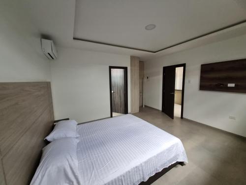 1 dormitorio con 1 cama blanca en una habitación en SUITES GARZOTA en Guayaquil