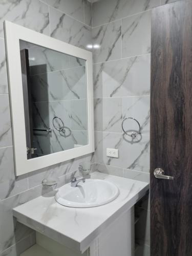 a white bathroom with a sink and a mirror at SUITES GARZOTA in Guayaquil