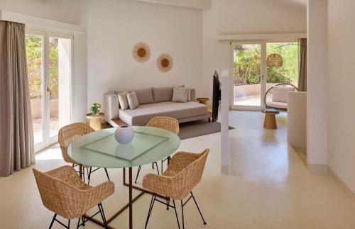 a living room with a table and chairs and a couch at Baia Di Chia Resort Sardinia, Curio Collection By Hilton in Chia