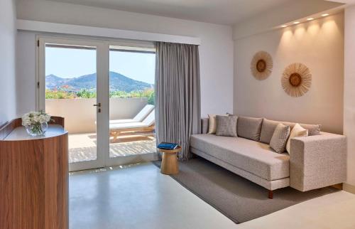 a living room with a couch and a sliding glass door at Baia Di Chia Resort Sardinia, Curio Collection By Hilton in Chia