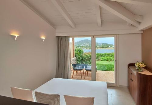 a room with a table and chairs and a large window at Baia Di Chia Resort Sardinia, Curio Collection By Hilton in Chia