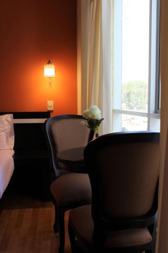 a room with two chairs and a bed and a window at Hotel PLATINIUM in Tacna