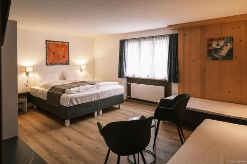 ein Hotelzimmer mit einem Bett, einem Tisch und Stühlen in der Unterkunft Gasthof Tenne in Lenk im Simmental