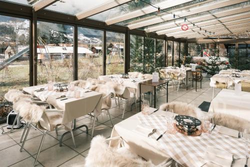 ein Restaurant mit weißen Tischen, Stühlen und Fenstern in der Unterkunft Gasthof Tenne in Lenk im Simmental