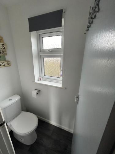 a bathroom with a white toilet and a window at 1st Floor family apartment Hillview in Brean