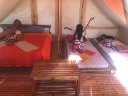drie kinderen op bedden in een tent bij Pandora Glamping in Quezon