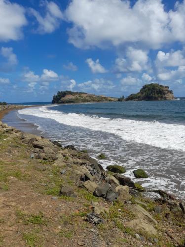 an empty beach with two islands in the water at Les Bromélias chez Djo et Rosy in Sainte-Marie