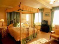 a bedroom with a canopy bed and a living room at Bishopsgate House Hotel in Beaumaris