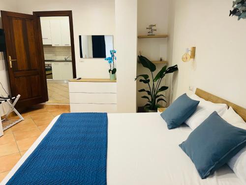a bedroom with a bed with blue pillows and a kitchen at Casa Saline in Tarquinia