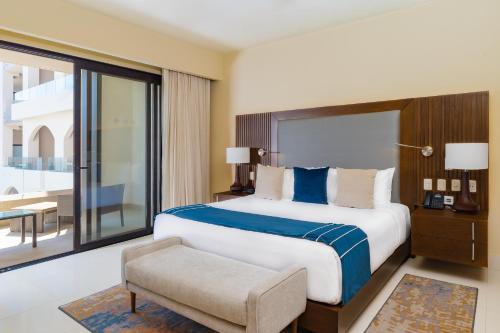 a bedroom with a large bed and a chair at Villa La Valencia Beach Resort & Spa Los Cabos in San José del Cabo