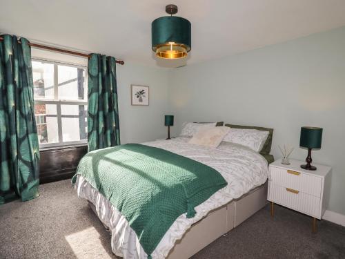 a bedroom with a bed with a green comforter and a window at Teulu in Llangollen