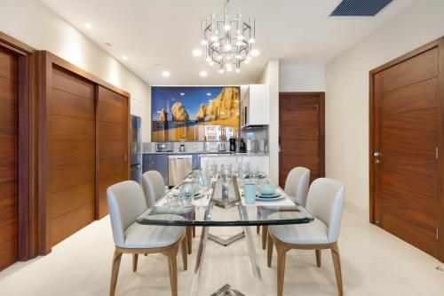 a dining room with a glass table and white chairs at Villa La Valencia Beach Resort & Spa Los Cabos in San José del Cabo