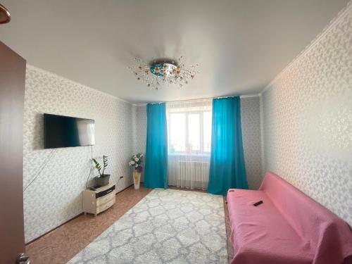 un soggiorno con divano rosa e finestra di Квартира a Kökşetaw